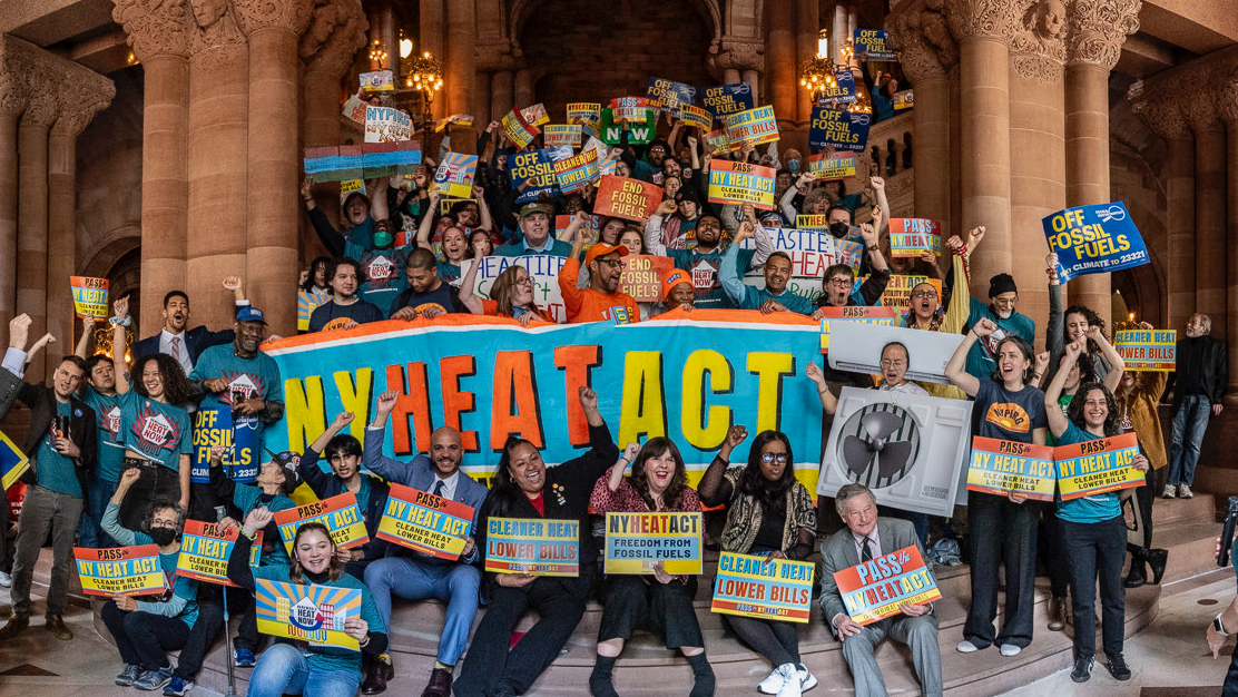 Crowd holding NY HEAT ACT signs